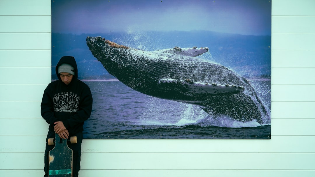 Person with skateboard next to whale artwork